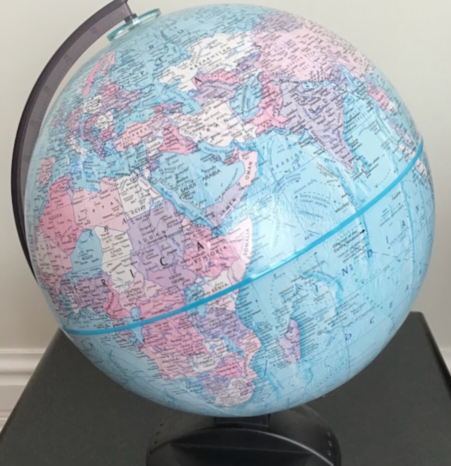 A world globe on a stand beside a bedside table