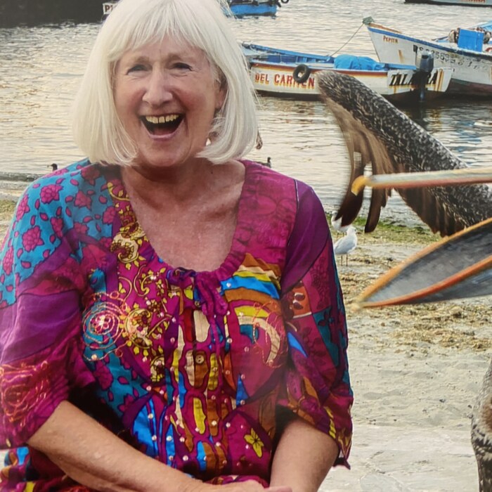 Smiling traveller in a sun hat standing by a harbour of fishing boats