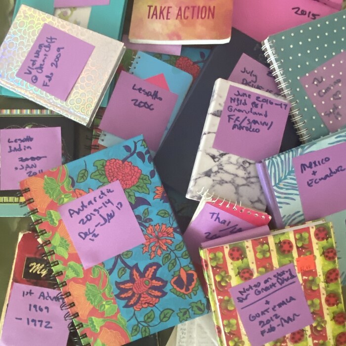 Handwritten travel journals, maps and postcards laid out on a desk