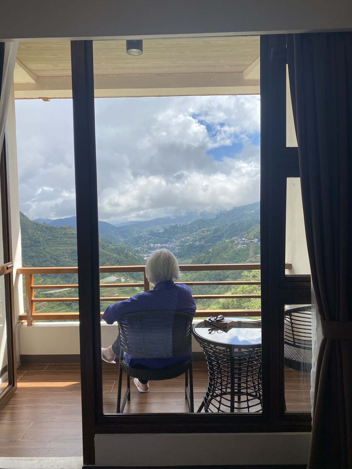 Joanne sitting on a balcony overlooking green mountains